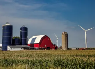 Landscape of Iowa farm with red barn, blue silos and windmills.