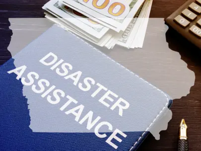 Disaster Assistance folder, money, calculator with State of Iowa map outline.